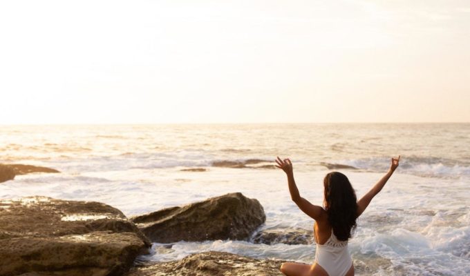 woman sitting in zen pose on beach