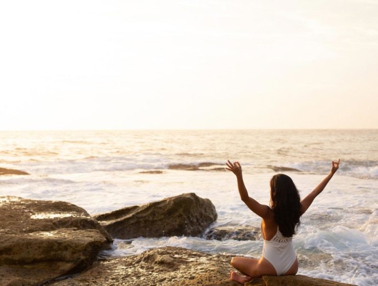 woman sitting in zen pose on beach
