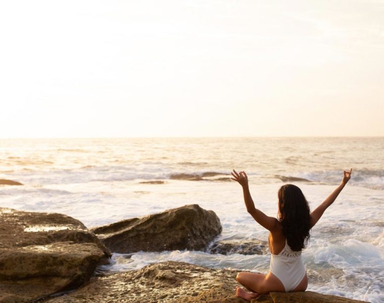 woman sitting in zen pose on beach