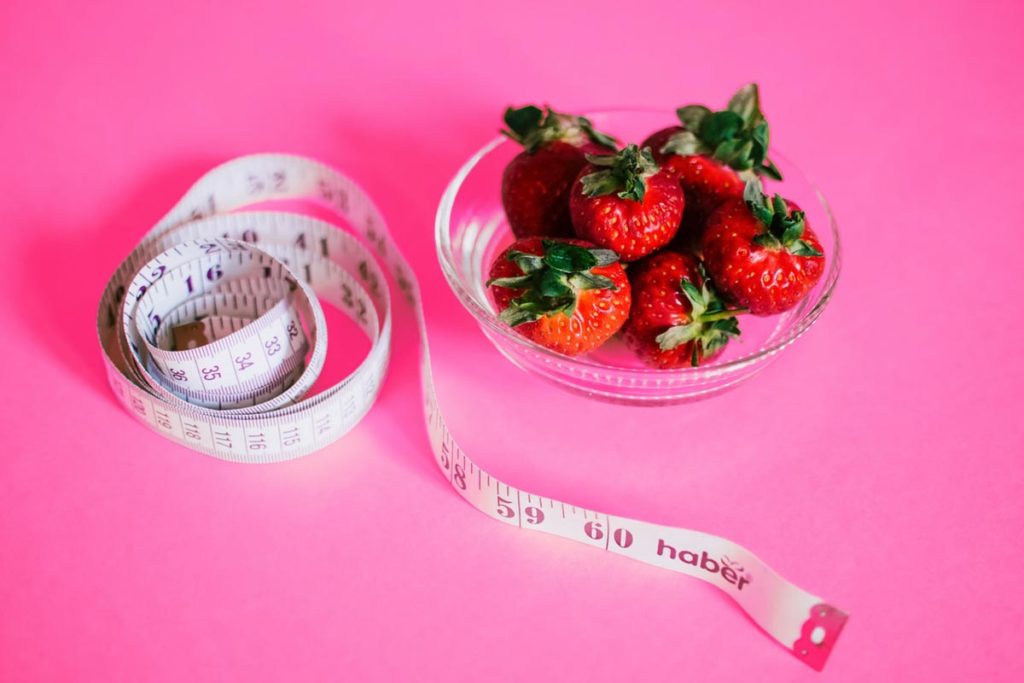Strawberries in a bowl next to a tape measure