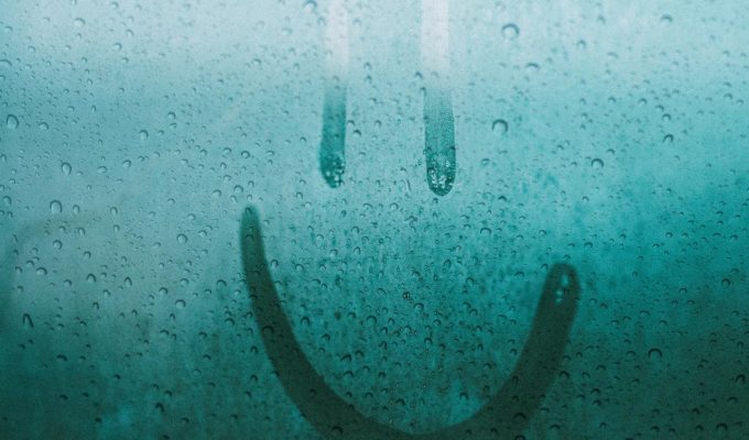smiley face drawn on a rainy window