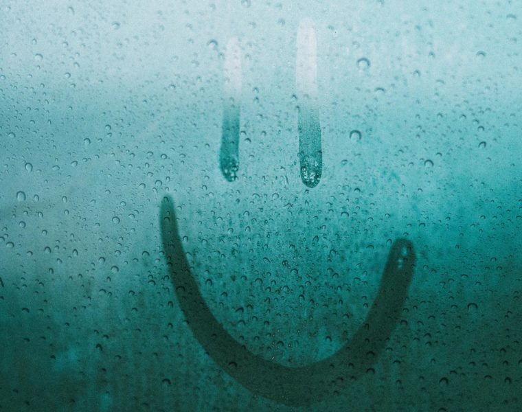 smiley face drawn on a rainy window